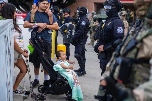 A family stand as law enforcement stand guard outside the Federal Building during a protest on Friday, June 13, 2025, in Los Angeles, California. A federal appeals court ruled on June 12 that the Trump administration can maintain control of the California National Guard, overturning a lower court ruling that U.S. President Donald Trump's deployment of troops to Los Angeles without Governor Gavin Newsom's consent as unlawful. Ringo Chiu/ZUMA Press Wire