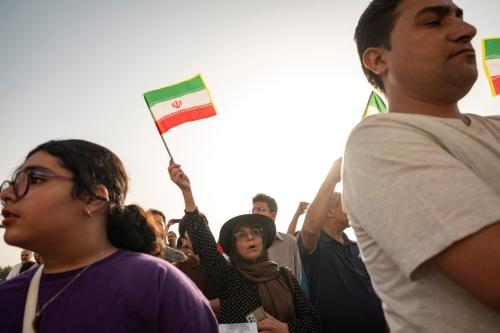 An Iranian woman waves a country's flag while standing at Azadi Square to watch a live concert in western Tehran, Iran, on June 25, 2025, as a ceasefire occurs between Iran and Israel.